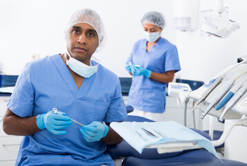 Latin american dentist working at modern dental office, preparing special medical tools