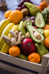 Winter healthy fruit wooden box with apples, kiwi, banana, avocado, ginger, pineapple, lemons, oranges and more ready for Christmass table.