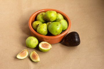 Top view of figs cut in half and figs in clay bowl on light brown background