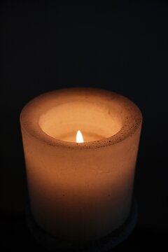 Brennende Kerze vor dunklem Hintergrund