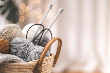Fototapeta na wymiar Cozy homely atmosphere. Female hobby knitting. Yarn in neutral shades in a soft basket
