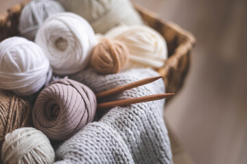 Fototapeta na wymiar Cozy homely atmosphere. Female hobby knitting. Yarn in neutral shades in a basket 