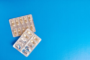 Vitamins in the form of capsules on a blue background. Treatment and prevention of diseases. Strengthening immunity.