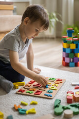 Male kid playing with wooden eco friendly alphabet letters board on table top view intellectual game