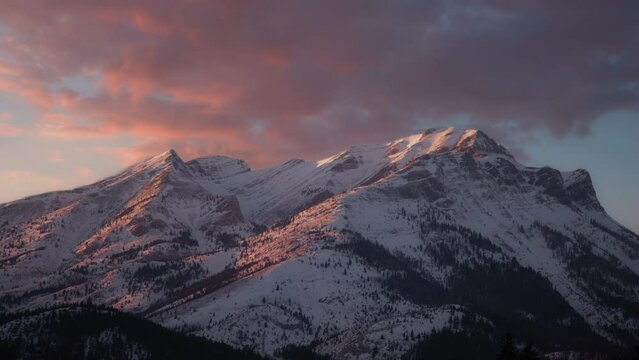 Epic sunset shining upon snowy mountain peaks lighting everything in vibrant colors. Zoom in. 