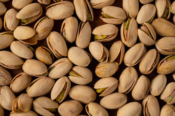 Close-up of roasted and salted cracked pistachios on a wooden table.