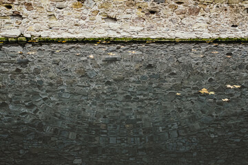 Ripples in the water of the canal, reflection of the stone wall, copy space for text.