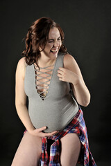 Beautiful pregnant woman laughing isolated on the black background - 553610843