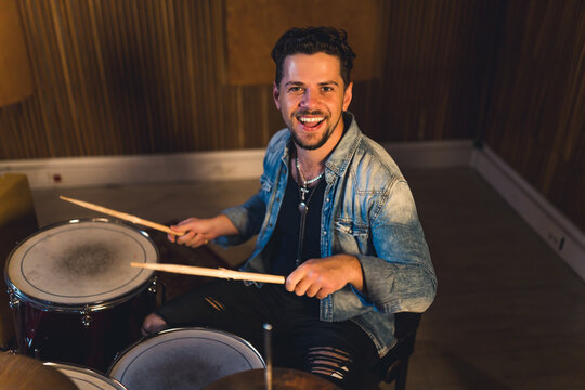 young cheerful man playing on drums in a studio, medium full shot musical studio music concept. High quality photo