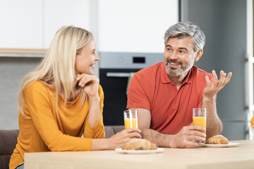 Happy loving couple having conversation while eating at kitchen