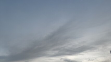 Light gray sky with clouds. Winter evening. High cirrus clouds of various shapes and sizes. The clouds are white in places translucent, through which a gray blue sky is visible.