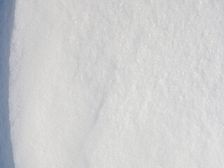 Beautiful winter background with snowy ground. Natural snow texture. Wind sculpted patterns on snow surface. Closeup top view with copy space.