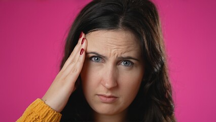 Fototapeta premium Closeup portrait of sick tired headache migraine exhausted displeased pretty woman 20s posing isolated on pink background studio. Put hands on head rub temples