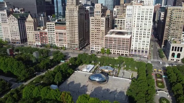 Aerial pan over Chicago Millennium Park aerial view of iconic Cloud Gate Bean by skyscrapers