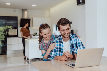 Father and daughter in modern house talking together on laptop with their family during holidays. The life of a modern family