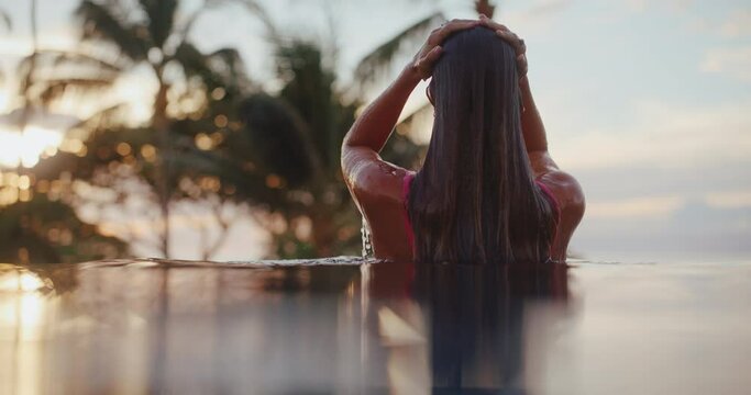 Woman relaxing in the pool at luxury resort spa at sunset, health and wellness rejuvenating tropical vacation