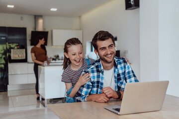 Obraz premium Father and daughter in modern house talking together on laptop with their family during holidays. The life of a modern family