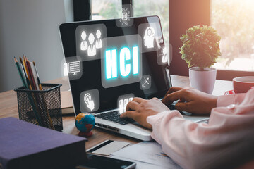 HCI concept, Human computer interaction, Person hand using computer on office desk with HCI icon on virtual screen.