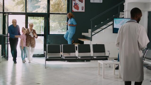 Elderly people taking sick niece to emergency checkup, feeling dizzy and light headed. Young child being unconscious in hospital reception, physician consulting girl with flashlight.