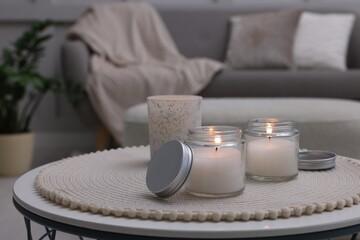 Burning candles in jars on white table indoors, space for text