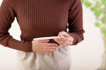 検査薬を見ながらお腹をさわる女性