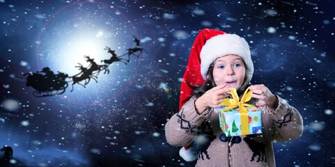 Fototapeta na wymiar Cute child in Santa Claus hat at night