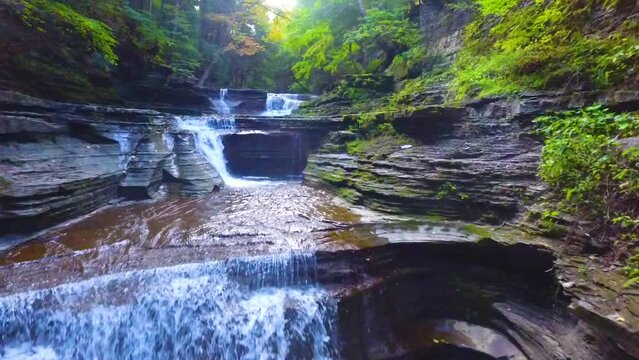 Aerial drone moving over gorge with stone staircase path and waterfalls