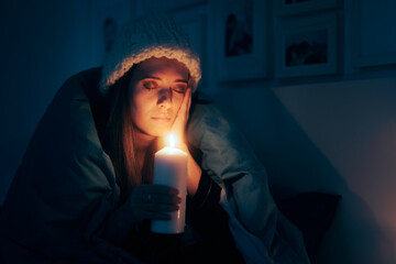 Unhappy Woman Feeling Cold Sitting in the Dark Using a Candle. Person freezing in her apartment...