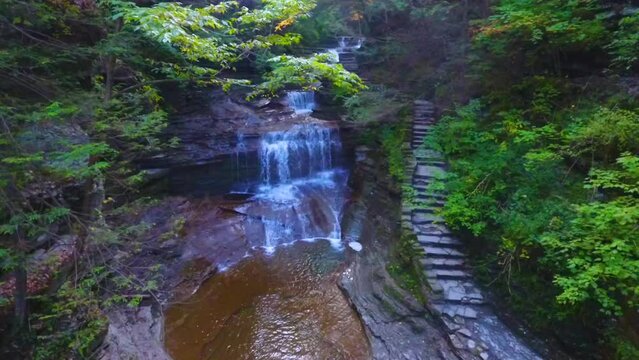 Aerial view going down into gorge with staircase and waterfall