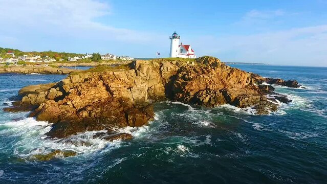 Aerial pan up at Nubble Lighthouse island off of Maine coast with ocean waves