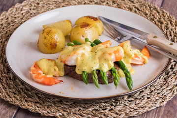 An above view of steak and asparagus with jumbo prawns and roasted potatoes.