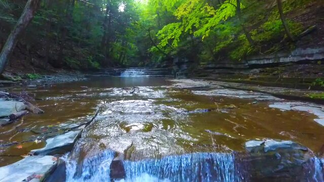 Aerial low and backwards over gorge with multiple tiers of waterfalls