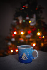 blue cup with hot on the background of a christmas tree with lights in the bokeh - 553626491
