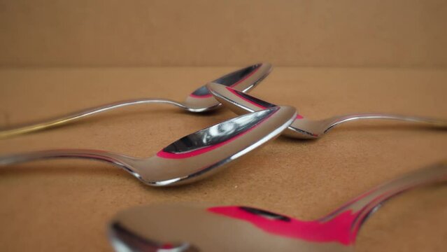 Stylish stainless steel tablespoons lie shining in cardboard package on wooden table reflecting bright studio colors macro