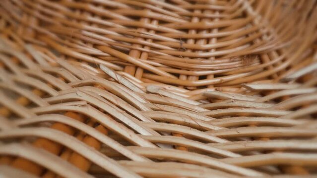 Large thick wicker hand-woven basket for fruit and mushrooms with handle made of willow lies on wooden table in studio room macro