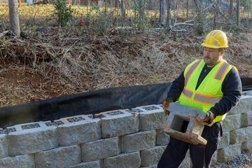 On construction site of new large block retaining wall contractor was seen installing new wall during installation process