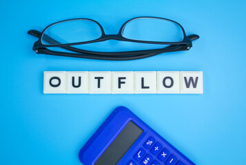 calculator and paper money with the word outflow. outflow concept. cash flow concept