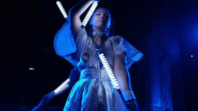 Light LED dance show. Beautiful young girl in a dress and a guy twist LED sticks in their hands. Impressive dance with luminous objects LED flashlights
