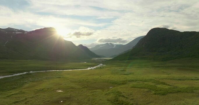 Magical sunlight shines past immense mountain peaks in Jotunheim Norway, drone shot