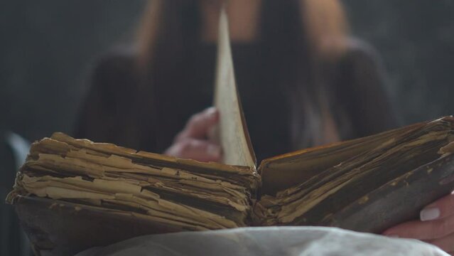 an old book in the hands of a woman. book with old pages. magical history book. old book, manuscript