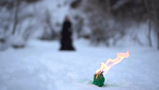 black witch on the background of fire. witch rite. mysticism and black magic. the witch walks in the snow