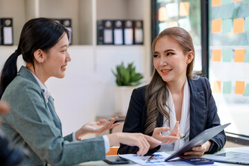 Fototapeta premium Two Young Asian businesswoman discuss with new startup project Idea presentation, analyze planning and financial statistics and investment market at office.