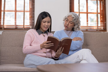Asian mother and daughter spent the holidays in the living room showing their love for each other by reading to their mother at home happily and warmly.