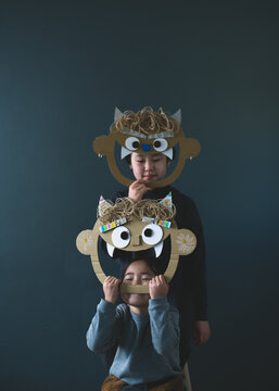 鬼のお面を持って黒い背景の前で笑う姉妹