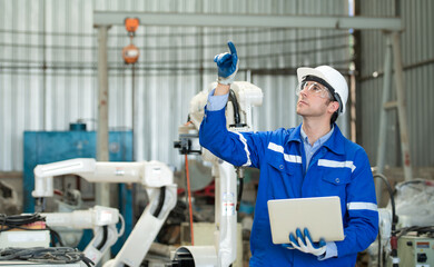 Young male engineers are manipulating a welding robot hand. By combining welding manipulation with...