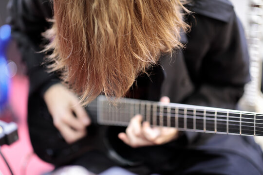 long hair rock guitarist playing electric guitar