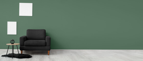 Comfortable black armchair and table near green wall. Banner for design