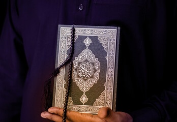 Man Holding Quran. Islamic Background. Arabic on the cover translated with Quran, Muslim man hands...