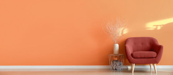 Comfortable armchair and table near orange wall. Banner for design