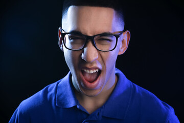 Portrait of emotional Asian man on black background